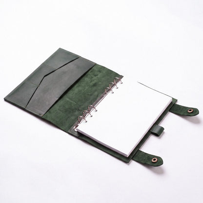 A dark green leather ring binder notebook cover with a white notepad inserted, photographed on a clean white background.